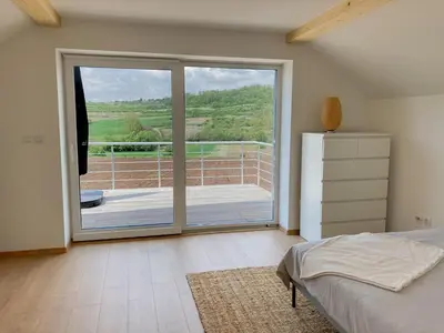 a bedroom with a large sliding glass door with a balcony at Agro Lux Apartment - Milenović in Soko Banja