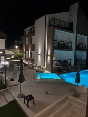 a swimming pool in front of a building at night at GOLDEN VIEW Sokobanja in Soko Banja