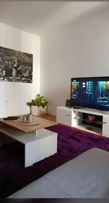 a living room with a table and a tv at Riviera Apartments in Niš