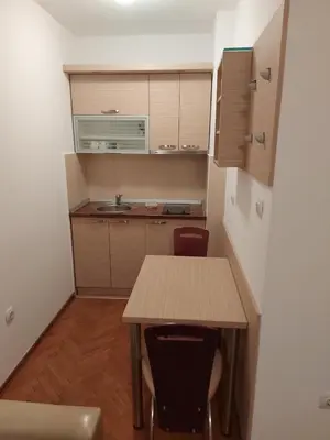 a small kitchen with a wooden table and chairs at Apartman Sneznik in Vrnjačka Banja