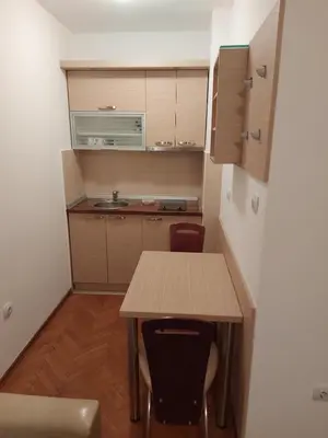 a small kitchen with a wooden table and chairs at Apartman Sneznik in Vrnjačka Banja