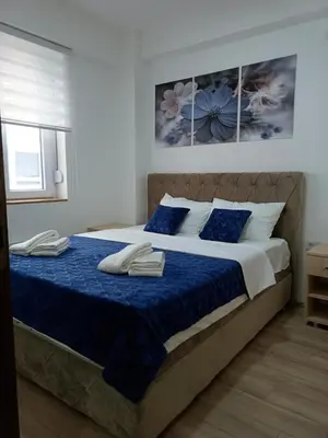 a bedroom with a large bed with blue sheets at Garden Hill Apartment in Jagodina