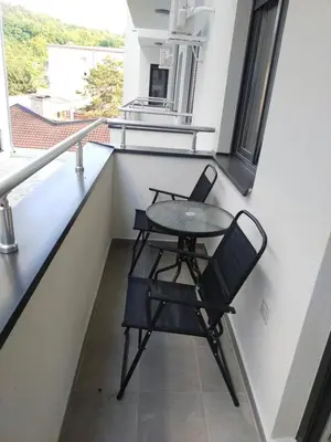 a small table and chair in a balcony with a window at Garden Hill Apartment in Jagodina