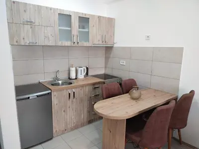 a kitchen with a wooden table and a sink at Garden Hill Apartment in Jagodina