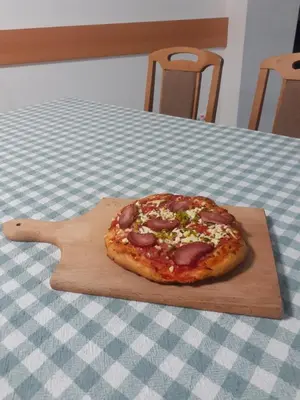 a pizza sitting on a wooden cutting board on a table at STD Cvetković in Crni Vrh