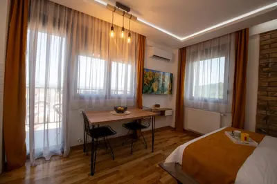 a bedroom with a bed and a table with chairs at Lux Apartman Sunce in Jagodina