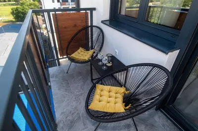 a balcony with two chairs with a yellow pillow at Lux Apartman Sunce in Jagodina