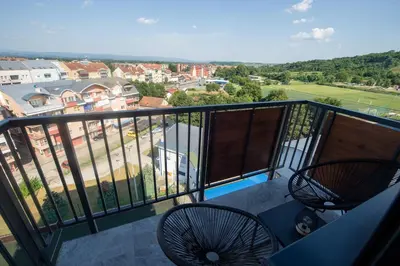 a balcony with two chairs and a view of a city at Lux Apartman Sunce in Jagodina