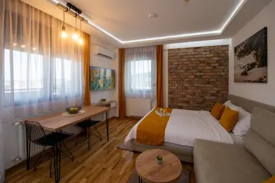 a bedroom with a bed and a couch and a table at Lux Apartman Sunce in Jagodina