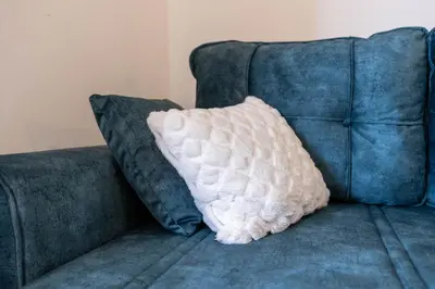 a white pillow sitting on top of a blue couch at Duma Apartmani Vrnjačka Banja in Vrnjci