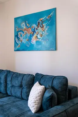 a blue couch in a living room with a painting at Duma Apartmani Vrnjačka Banja in Vrnjci