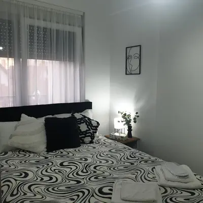 a bedroom with a bed with a black and white comforter at Apartman Dunjic in Vrnjačka Banja