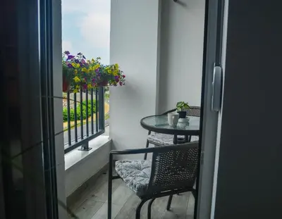 a table and a chair on a balcony with flowers at Apartman Dunjic in Vrnjačka Banja