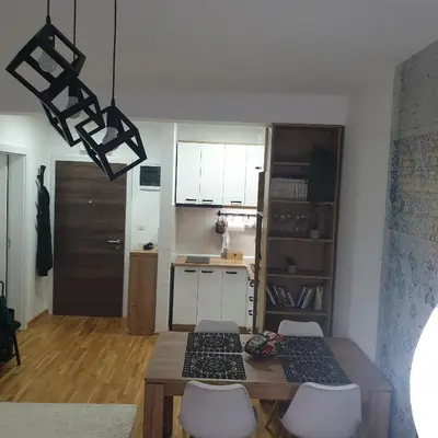 a kitchen with a wooden table and white cabinets and a dining room at Apartman Dunjic in Vrnjačka Banja
