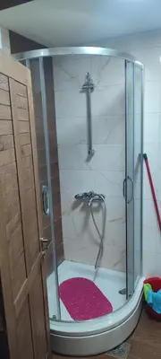 a shower with a glass door with a red rug at Vidik suite in Kopaonik
