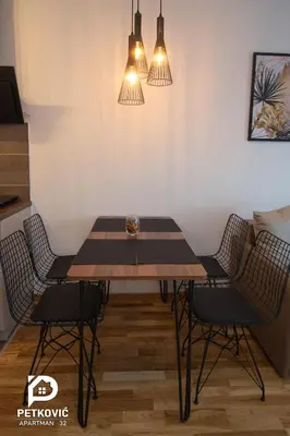 a dining room with a wooden table and chairs at Petković apartmani STUDIO32 in Jagodina