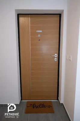 a wooden door in a room with a mat in front of it at Petković apartmani STUDIO32 in Jagodina