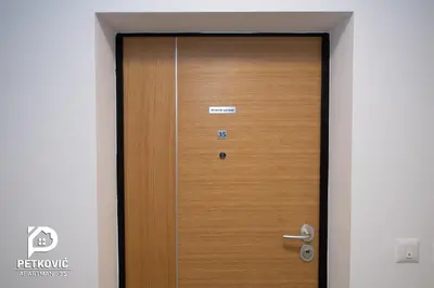 a wooden door in a hallway with a sign on it at Petković apartmani 35 in Jagodina
