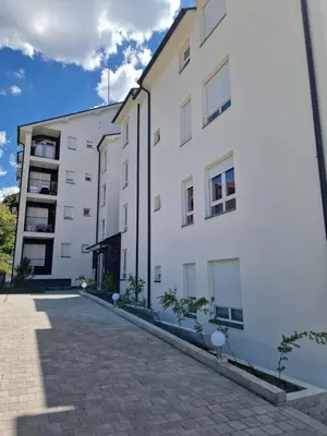 a white apartment building with a cobblestone street at Apartman Pavlović in Soko Banja