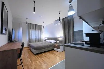 a bedroom with a bed and a kitchen with a desk at Cozy and Lovely Apartments I & II in Jagodina
