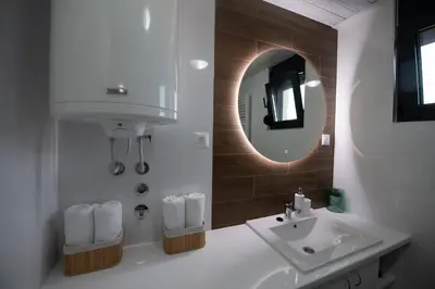 a white bathroom with a sink and a mirror at Lux Apartman Petrovic in Jagodina