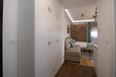 a hallway with white walls and a couch in a room at Lux Apartman Petrovic in Jagodina