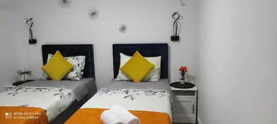 a bedroom with two beds with yellow pillows at Apartmani Simić in Kuršumlija