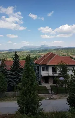 a house with a red roof and some trees at Apartment Vojinović in Soko Banja
