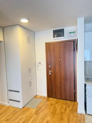 an empty room with a wooden door and a kitchen at Mirabela Apartman Sokobanja in Soko Banja