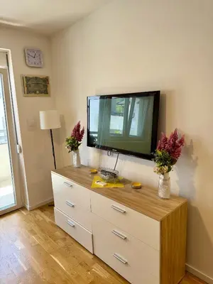 a living room with a dresser with a tv on the wall at Mirabela Apartman Sokobanja in Soko Banja