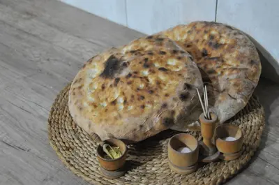 two large breads on a wicker basket with small pots at Domaćinstvo Ukusno Marković in Brusnik