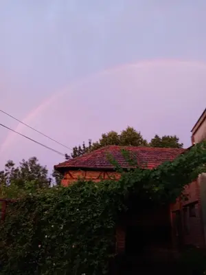 a rainbow in the sky above a house at Domaćinstvo Ukusno Marković in Brusnik