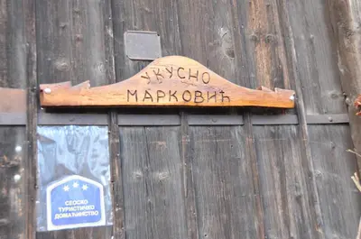 a wooden sign hanging on a wooden fence at Domaćinstvo Ukusno Marković in Brusnik