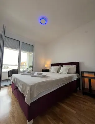 a bedroom with a large bed with a blue clock on the ceiling at Lux apartment 8, center, free parking in Niš