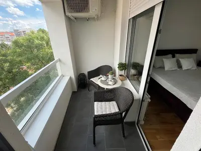 a balcony with a table and chairs and a bed at Lux apartment 8, center, free parking in Niš