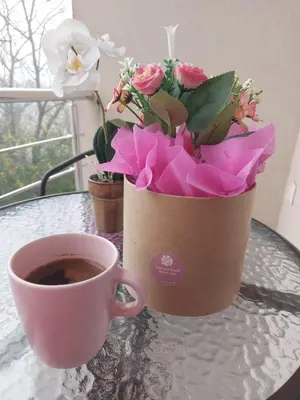 a cup of coffee and a bouquet of flowers on a table at Apartman Vera in Vrnjačka Banja