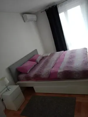 a bedroom with a bed with pink pillows and a window at Apartman Vera in Vrnjačka Banja