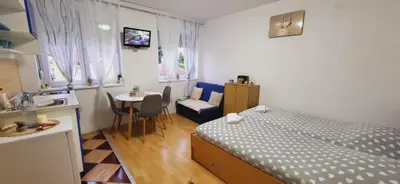 a bedroom with a bed and a table and a kitchen at Apartman Marta in Vrnjačka Banja