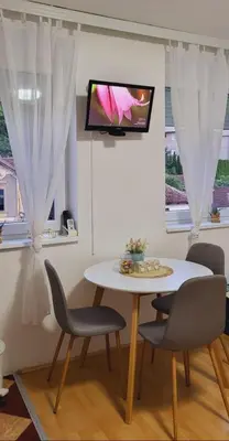 a white table and chairs with a tv on a wall at Apartman Marta in Vrnjačka Banja