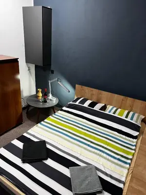 a bed with a striped blanket and a table at Calipso1 in Niš