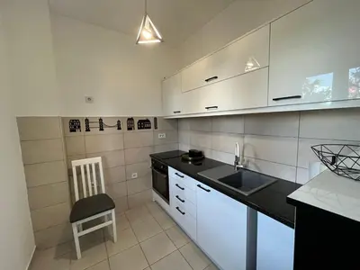 a kitchen with white cabinets and a sink and a chair at Apartment Esperanto next to the Aqua Park in Jagodina