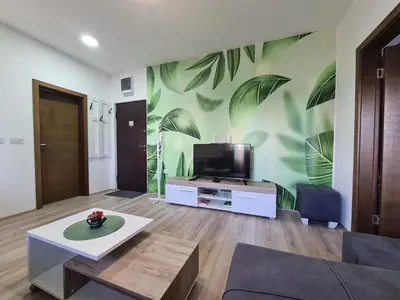a living room with a tv and a mural of leaves at Apartment Esperanto next to the Aqua Park in Jagodina