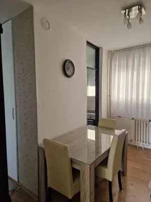 a dining room table with chairs and a clock on the wall at Esperanto in Vranje