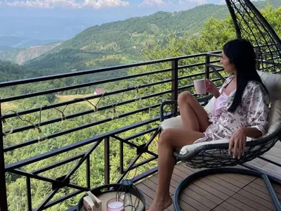 a woman sitting in a chair with a cup of coffee at Mon réve Nlux79 in Kopaonik