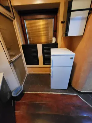 a small white refrigerator in a room with a window at LENA Apartman 45m2 Sokobanja-CENTAR in Soko Banja