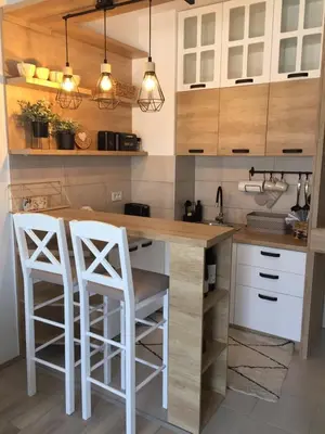 a kitchen with white stools at a wooden counter at Apartman Mijatovic in Jagodina