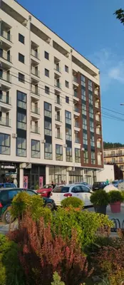 a large building with cars parked in a parking lot at Apartman Mijatovic in Jagodina