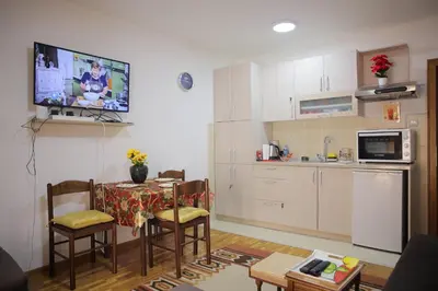 a kitchen and dining room with a table and a tv at Zlatni apartman in Vrnjačka Banja