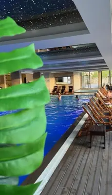 a swimming pool with chairs and people in the water at Majapartman in Kopaonik
