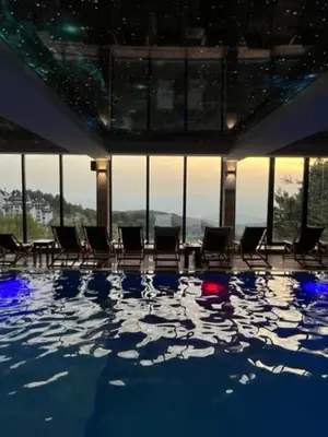 a swimming pool with chairs in a building with windows at Majapartman in Kopaonik